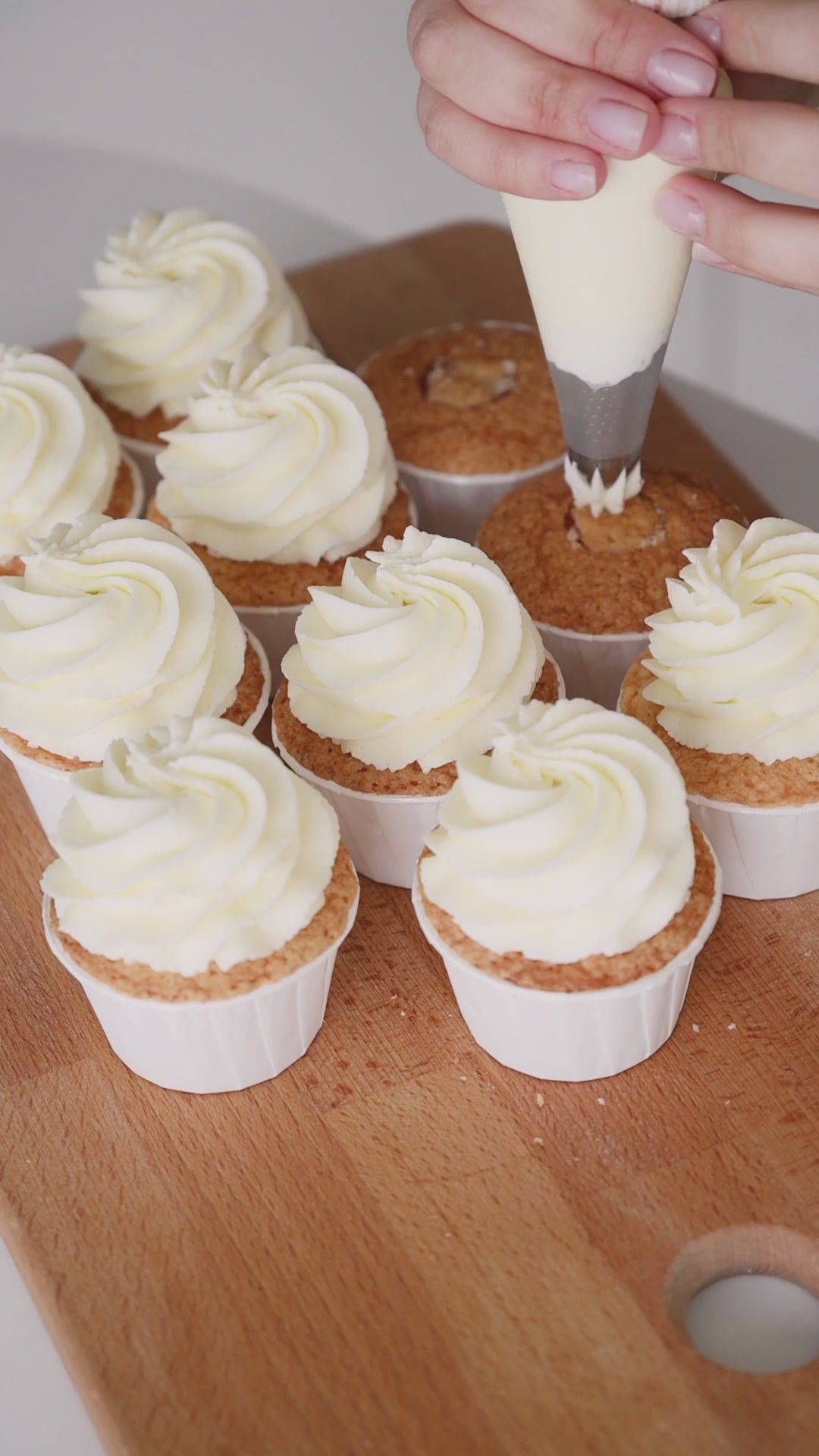 Piping butter cream overtop of cupcakes